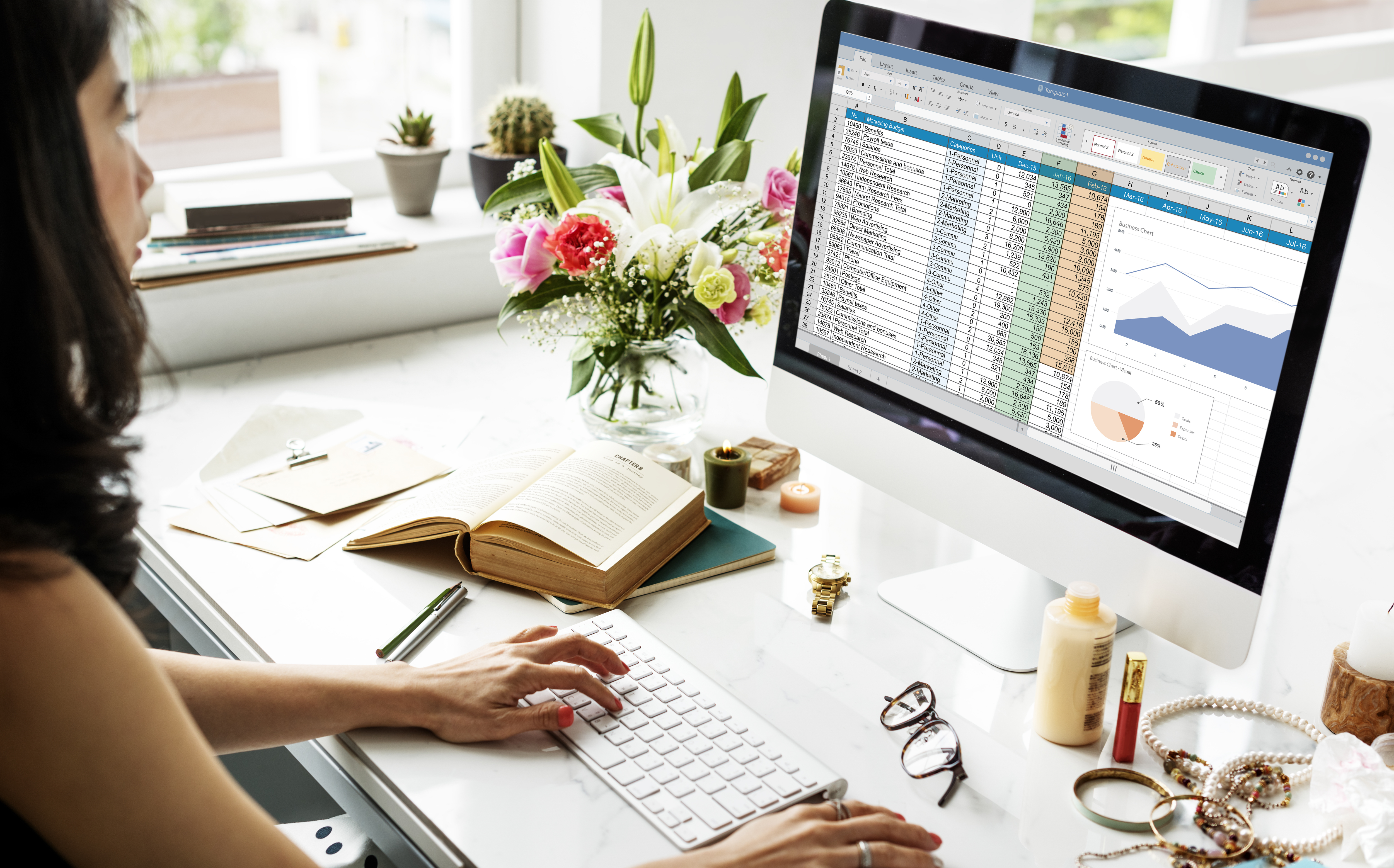 A person performing data entry on a computer with charts in the background